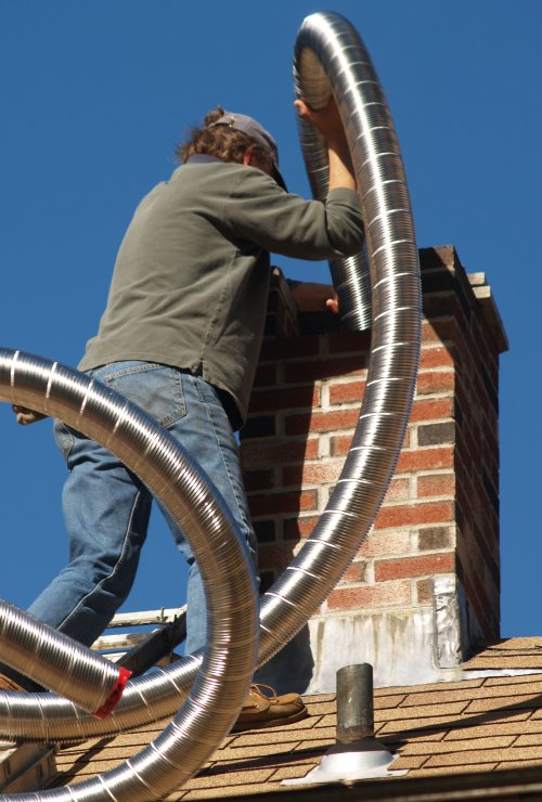 repair man pushing a hose down a chimney